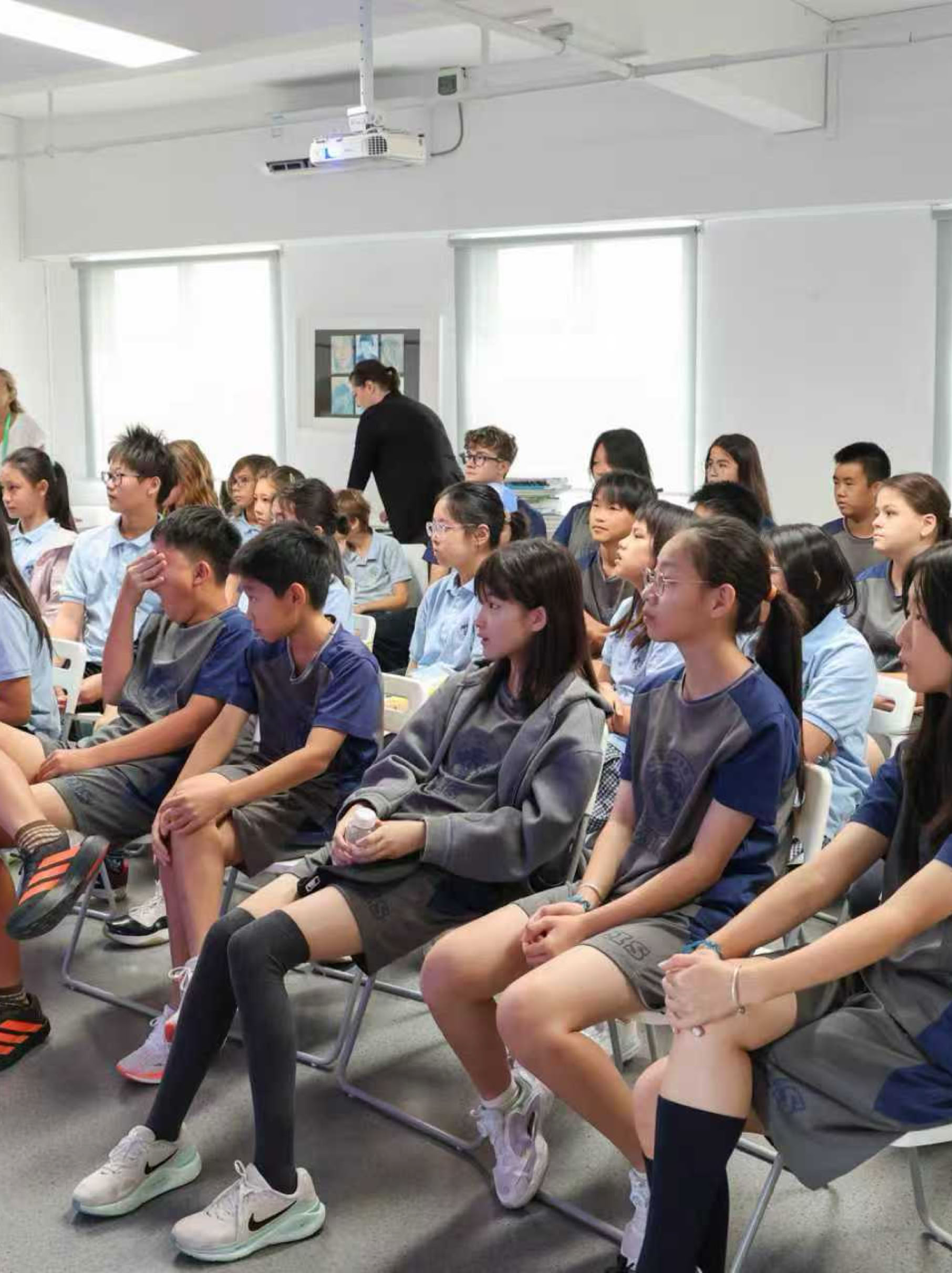 A group of children in soccer uniforms standing on a field, some holding a trophy and others cheering, with buildings and a cloudy sky in the background.